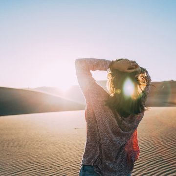 Femme dans le désert face au soleil levant